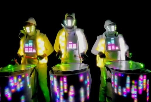 Vibrant Lighted Drummers. Light-up drummers in neon suits, performing with illuminated drums at night.