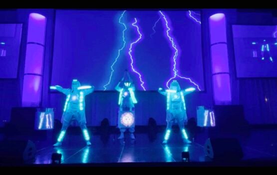 Energetic Mixd Elements Dance Crew performing futuristic LED dance show with lightning effects. Bright LED costumes enhance their dynamic dance moves against lightning backdrop.